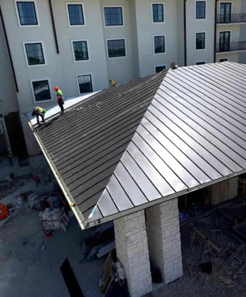 Crew installing standing seam metal roof panels on a commercial project in Mecca
